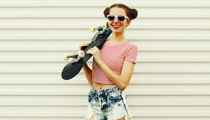 Summer portrait of cheerful smiling young woman with skateboard on a white background