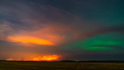 Obraz premium Northern lights battling the lights from a forest fire 