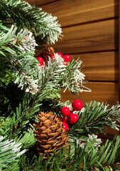 Close-up artificial Christmas tree with some ornaments and soft blur in the wooden background on the right.