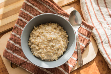 Healthy and dietary oatmeal in a gray deep plate top view.
