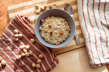 Healthy, dietary and nutritious oatmeal with hazelnuts in a gray plate on the table top view.