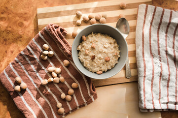 Healthy, dietary and nutritious oatmeal with hazelnuts in a gray plate on the table top view.