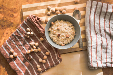 Healthy, dietary and nutritious oatmeal with hazelnuts in a gray plate on the table top view.