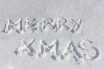 Hand drawn inscription Merry Christmas on white surface of snow. Greeting card. Christmas concept.Top view. Flat lay.
