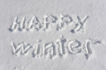 Inscription Happy winter, written on white surface of the snow . Top view. Flat lay. Winter holiday concept