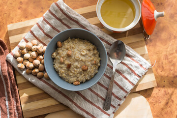 Healthy, dietary and nutritious oatmeal with delicious homemade honey, hazelnuts in a gray plate on the table top view.