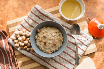 Healthy, dietary and nutritious oatmeal with delicious homemade honey, hazelnuts in a gray plate on the table top view.
