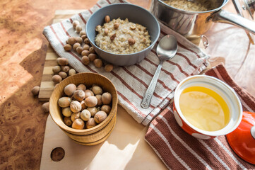 Healthy, dietary and nutritious oatmeal with delicious homemade honey, hazelnuts in a gray plate on the table top view.