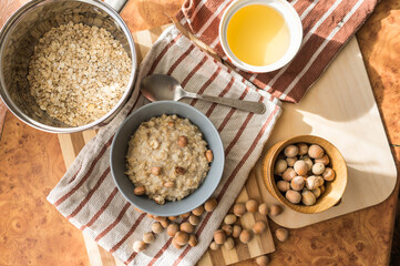 Healthy, dietary and nutritious oatmeal with delicious homemade honey, hazelnuts in a gray plate on the table top view.