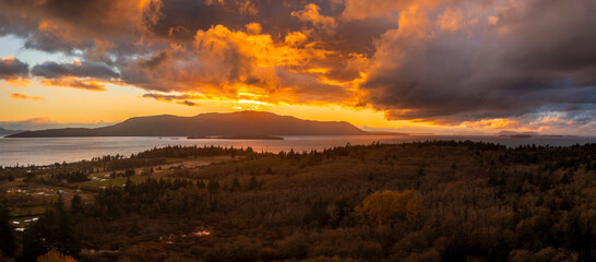 Fiery Red Sunset Over Orcas Island, Washington. After a torrential rain storm the clouds finally opened up and as the sun set it turned the clouds bright red and orange. Aerial taken from Lummi Island
