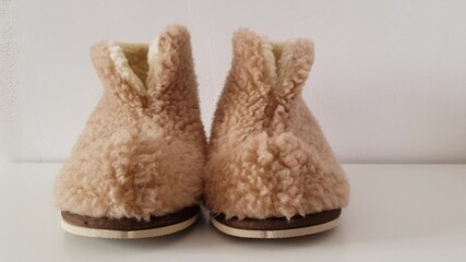 Warm winter slippers made of sheepskin on white floor