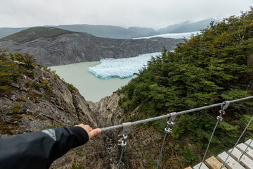 A woman's hands holds a wire rope of the pedestrian suspension bridge, Torres del Paine National Park, Chile