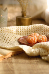 Peeled tangerines, butternut squash, open book, reading glasses and cozy blanklet. Hygge at home. Selective focus.