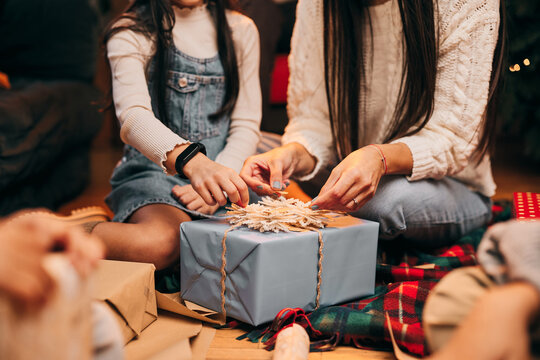Close up of mother and daughter decorating Christmas gifts while sitting on the floor at home.