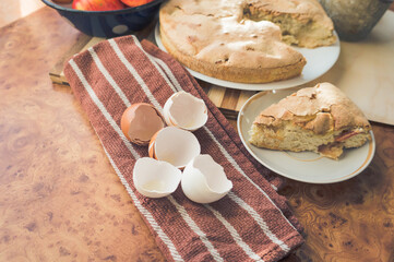 Homemade and puffed apple biscuit and sliced ​​pie in a saucer on the table.