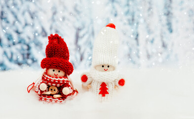 Two little doll girls in the snow, wintertime, christmas season, greeting card, trees in the background