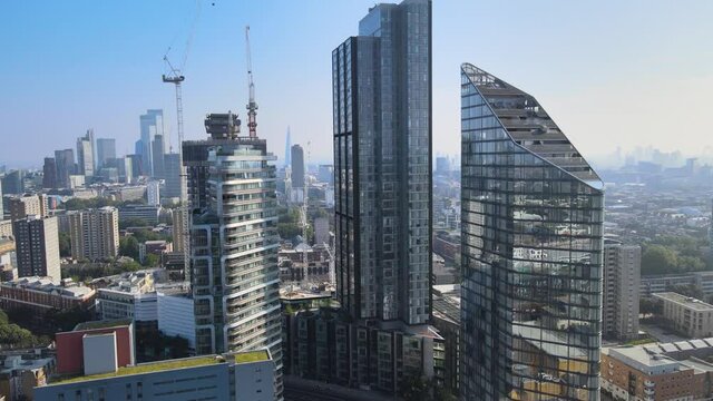 Fly around modern residential block, tall apartment buildings. Cranes on construction site, panoramic view of city. London, UK