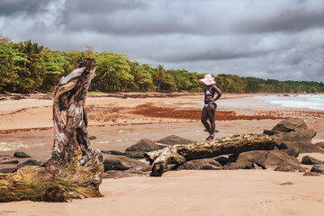 African woman walking on an old wooden log by the tropical beach in Axim Ghana West Africa