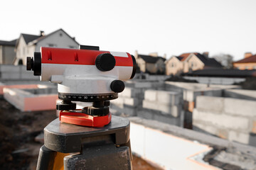 Theodolite on a tripod against the background of building a house. Niveler