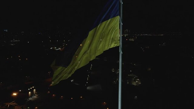 Gorgeous aerial view of night Kyiv and the Ukrainian flag flailing in the wind