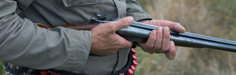 Hunter man in camouflage with a gun during the hunt in search of wild birds or game. Autumn hunting season.