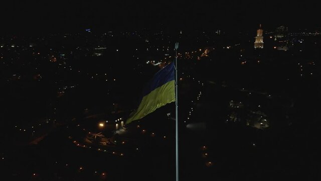 Drone footage of the flag of Ukraine flailing in the wind at night, Kyiv