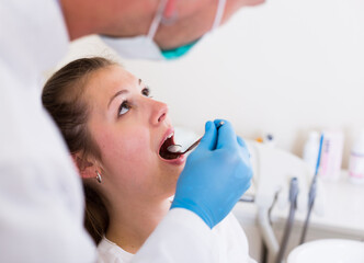 Fototapeta premium Adult doctor in uniform is taking visional inspection of a girl in clinic.