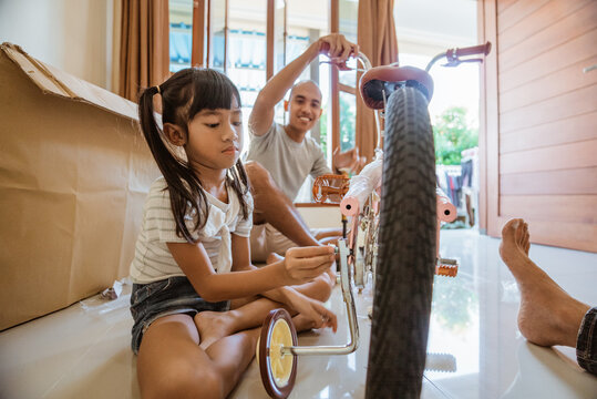 Asian girl installs auxiliary wheel bolts on new mini bike