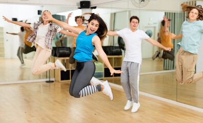 Fototapeta na wymiar Group of teenagers jumping together during dance class in studio.