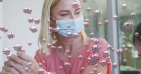 Animation of covid 19 cells over caucasian blonde mother and her daughter in face masks - Powered by Adobe