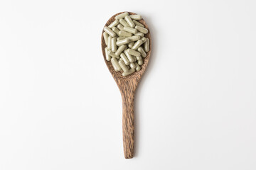 Many pill capsules in a wooden spoon on white background