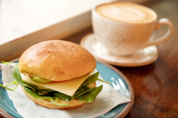 Vegetarian breakfast sandwich with cappuccino coffee drink at a trendy coffee shop.
