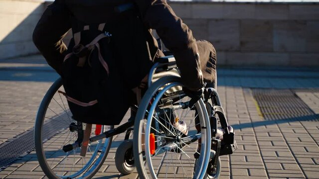 man in manual wheelchair is moving on street in modern city, equipment for disabled people