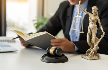 Fototapeta premium the goddess of justice with scales and hammers placed in front of a Male lawyer working on a laptop legal concept. Advice on Justice in the Lawyer's Office