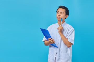 Handsome young male nurse concentrating thinking of ideas over blue background