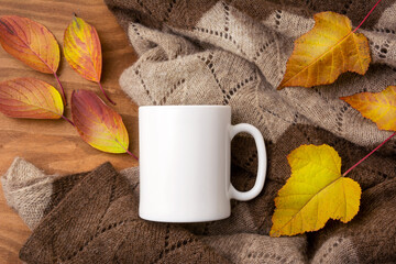 White coffee mug mockup with knitted blanket and fall colorful leaves