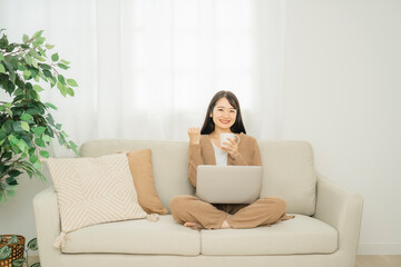Obraz na płótnie Canvas 家でノートパソコンを使う女性（ソファ・ガッツポーズ） 