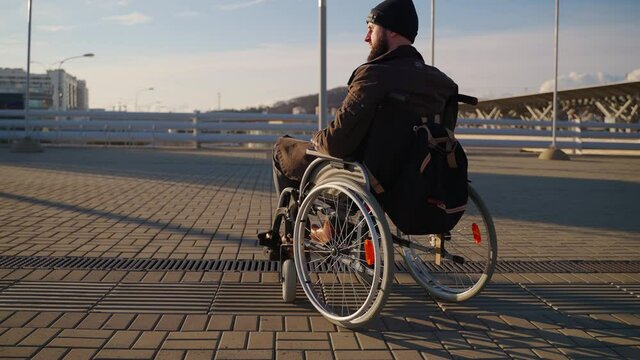 adult man is sitting in manual wheelchair, using invalid carriage for moving