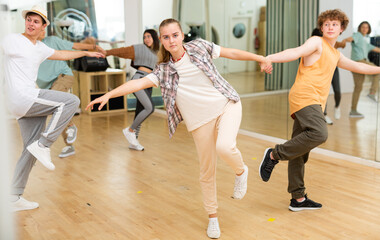 Portrait of teenage girl learning to dance vigorous cheerful lindy hop in pair with boy in choreography class.