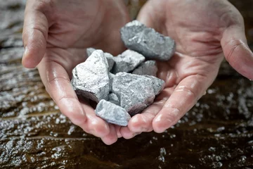 Fotobehang The wet man's hand was holding silver, or platinum, or rare earth minerals. © Phawat