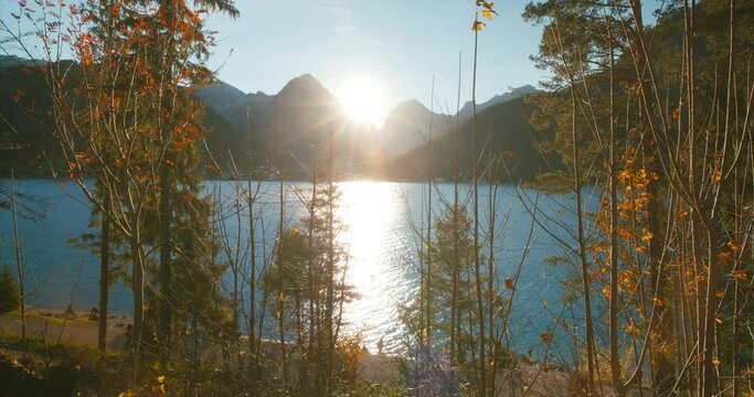 Distant view of people on walking trail by scenic view of alps mountains at lake achensee in sunset golden hour in Austria, Europe. Wide Angle.