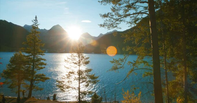 People walking by a group smoking near walking trail by scenic view of alps mountains at lake achensee in sunset golden hour in Austria, Europe. Wide Angle.