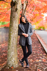 Biracial Asian teen girl enjoying fall autumn leaves along road