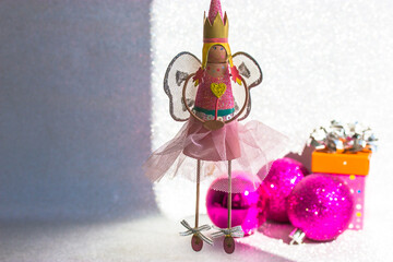 Toy fairy in pink dress with crown on head and wings holding magic wand with heart image in hands....
