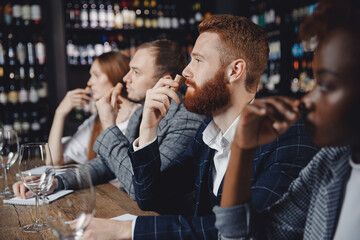 Young man listens to aroma of red wine at master class tasting in restaurant, training sommelier