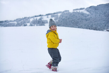 Fototapeta na wymiar Cute little girl on snow winter nature. Funny kid in winter clothes. Children play outdoors in snow. Kids Christmas vacation.