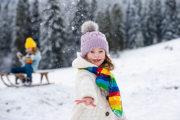 Lovely child girl playing snowball fight on a winter walk in snow nature.