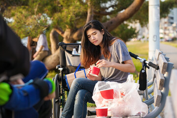 Fototapeta na wymiar Biracial teen girl on park bench outdoors eating takeout food