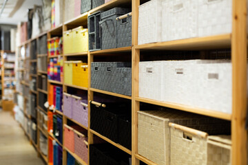 Variety of decorative storage boxes displayed on shelving in household goods store. Concept of...