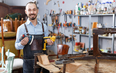 Confident workman using tools while working at repair shop, renovating vintage chair